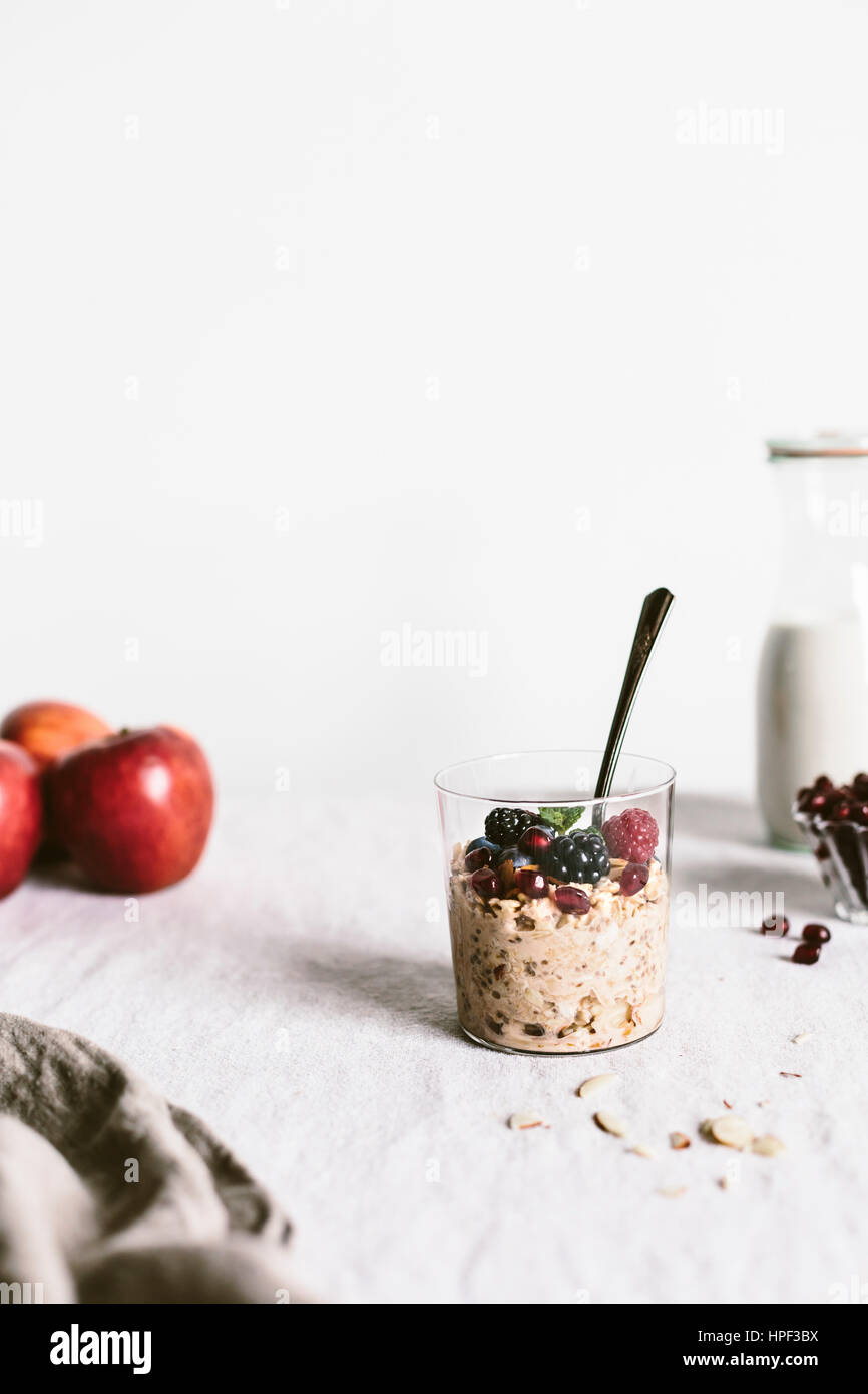 A clear glass of apple muesli topped off with berries are photographed from the front view. Stock Photo