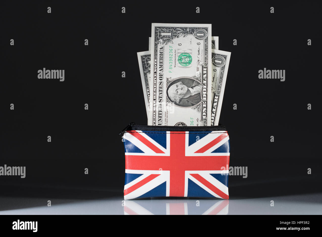 Union Jack coin purse with US Dollars set against dark background. Metaphor US Dollar-Sterling exchange rate and trade, holiday spending money in US. Stock Photo