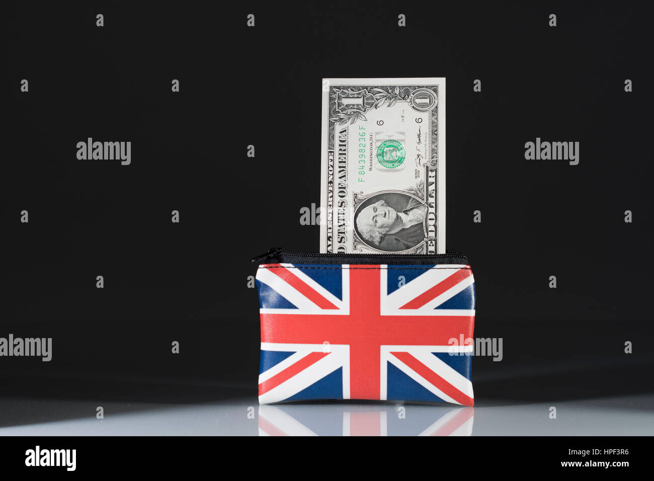 Union Jack coin purse with US Dollars set against dark background. Metaphor US Dollar-Sterling exchange rate and trade, holiday spending money in US. Stock Photo