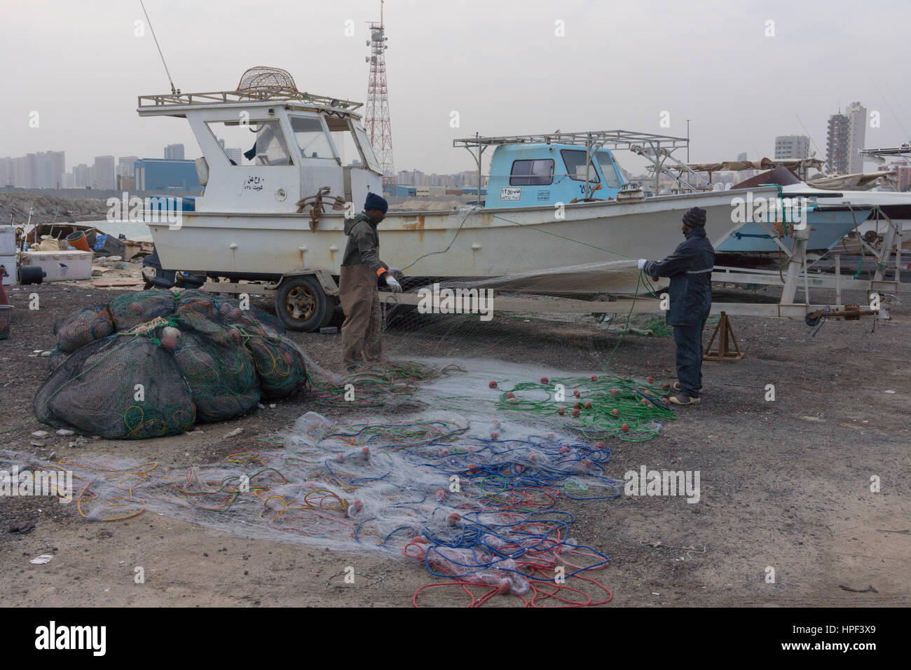 Migrant fishermen working on nets in a harbour in Kuwait. Stock Photo