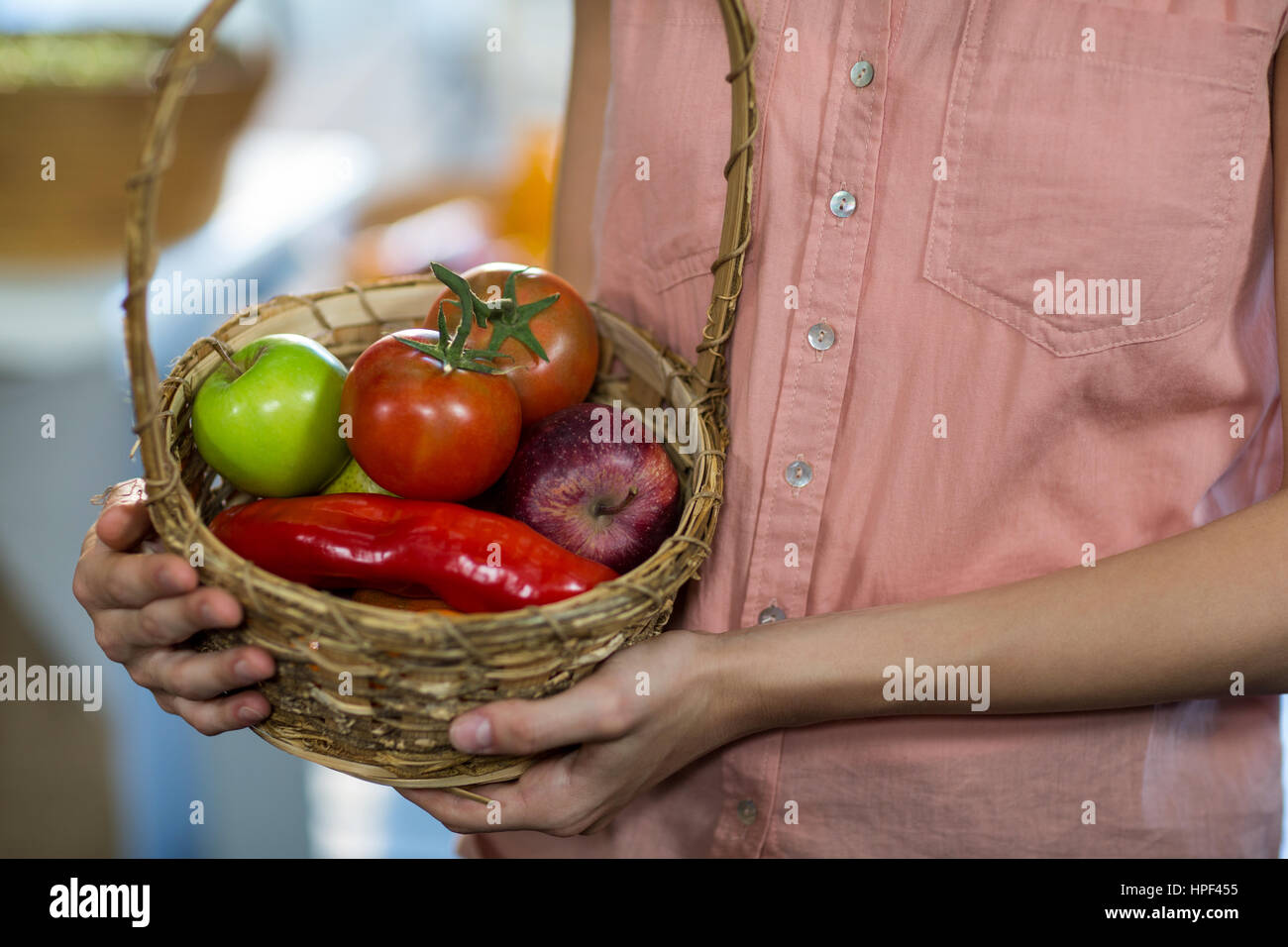 Mid-section of woman holding a basket with variety of fruits and ...