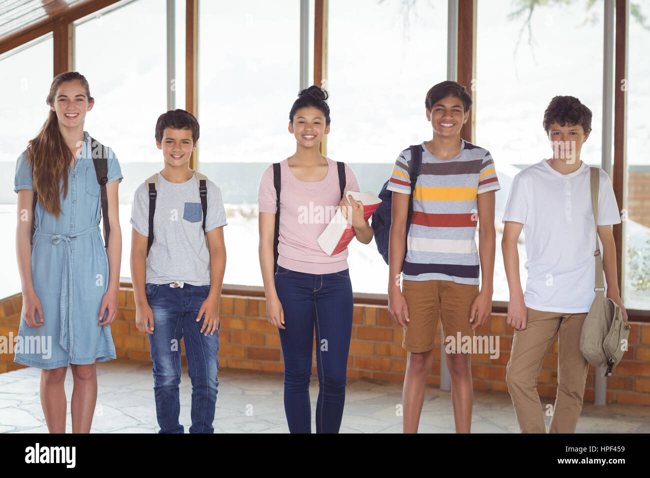 Portrait of happy students standing in corridor at school Stock Photo ...