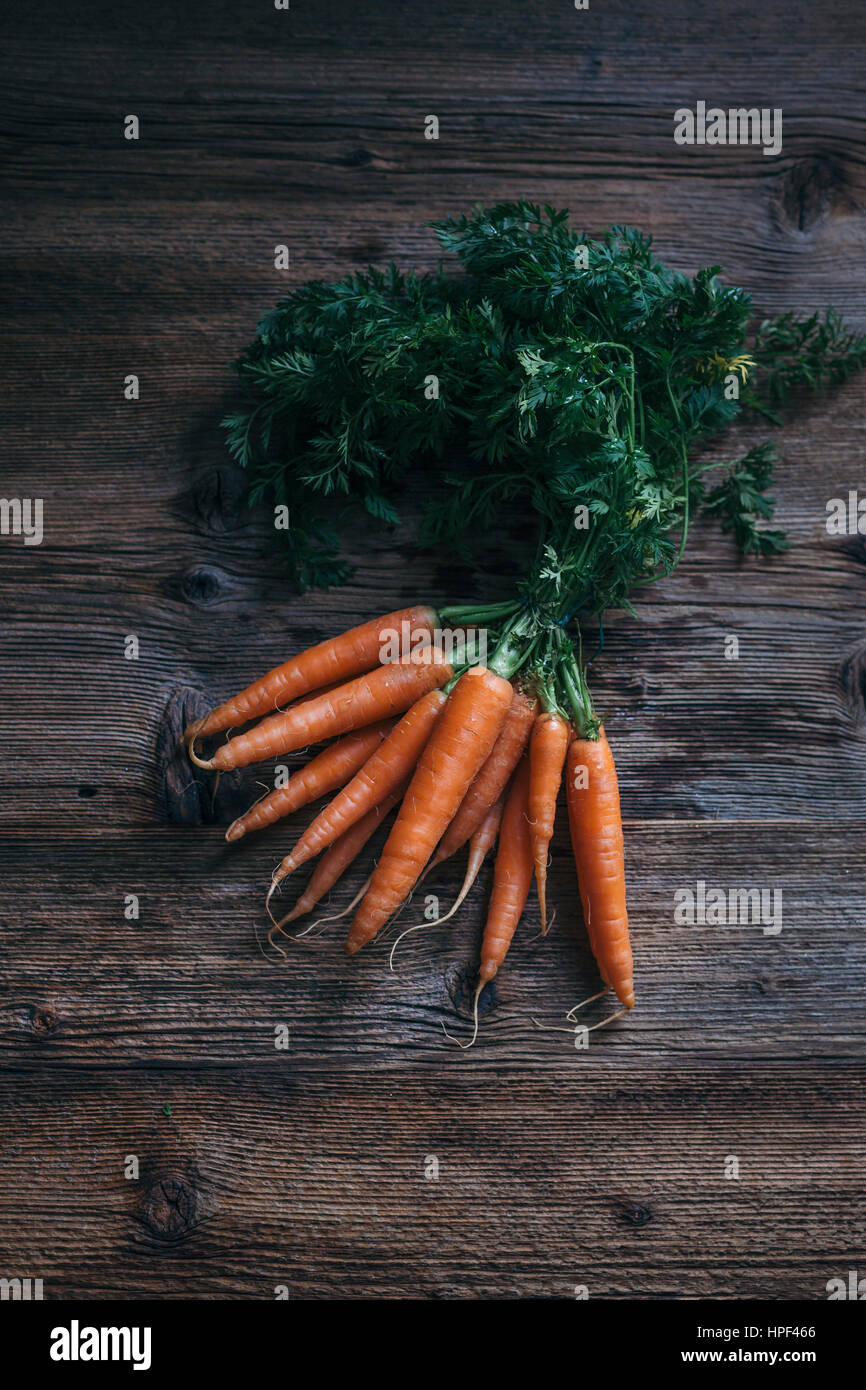 Bunch of fresh carrots on a rustic wooden table Stock Photo