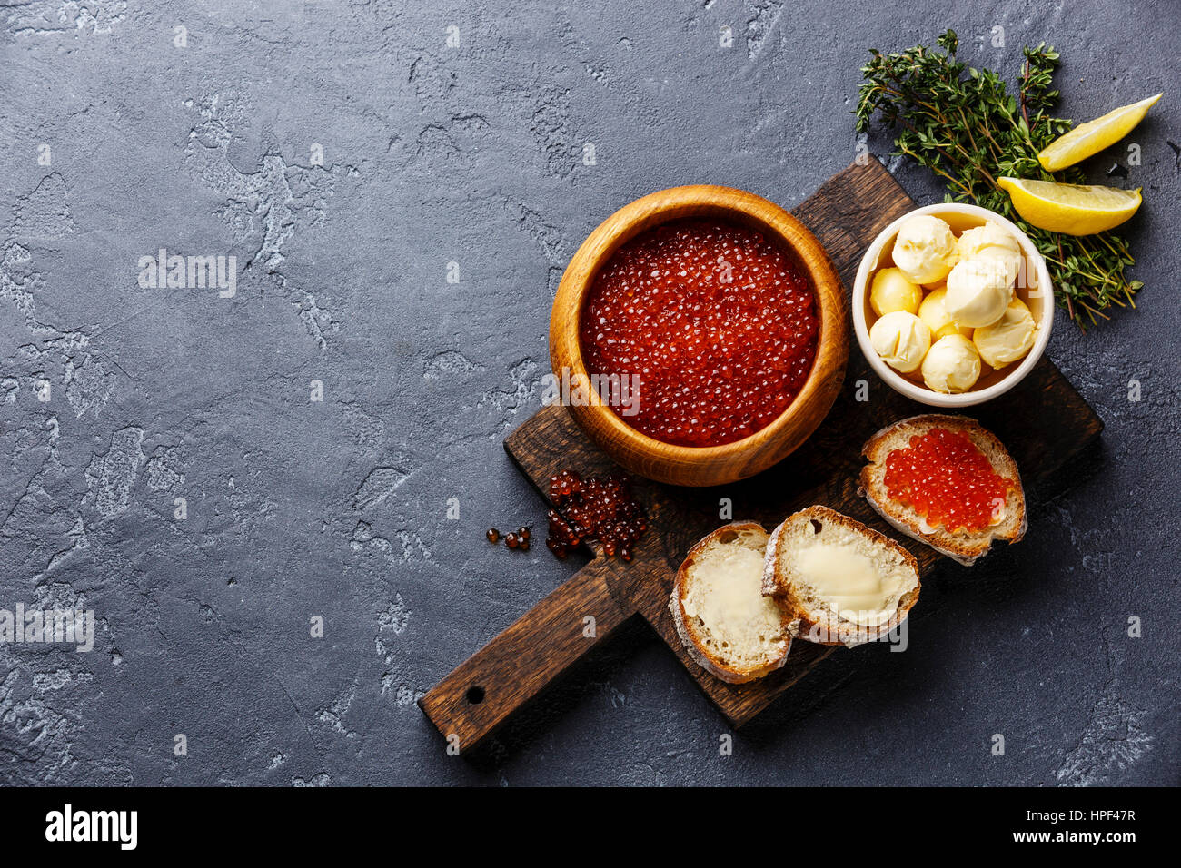 Salmon red caviar in wooden bowl and Sandwiches on dark stone background copy space Stock Photo