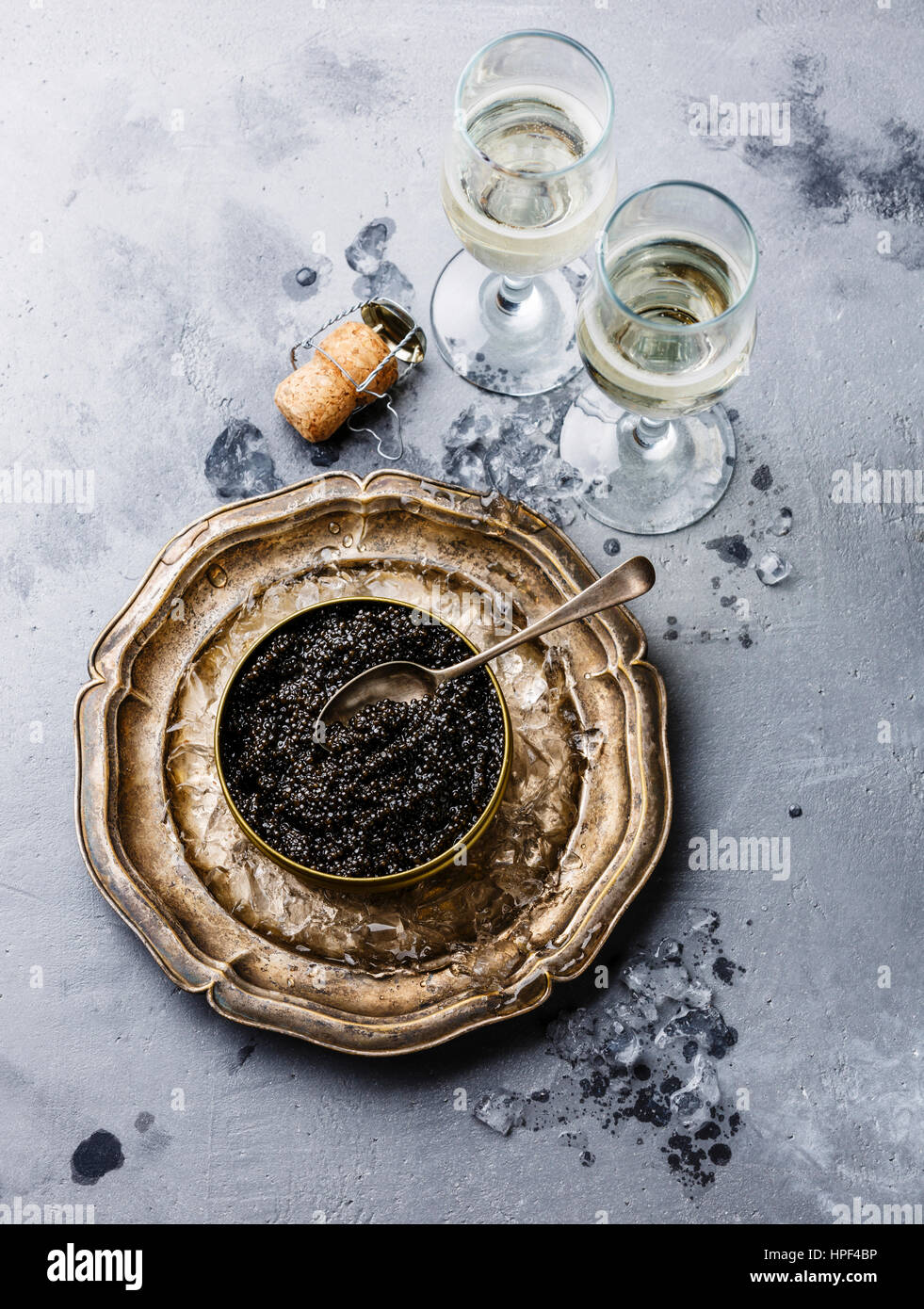 Black Sturgeon caviar in can on ice and champagne on concrete background Stock Photo