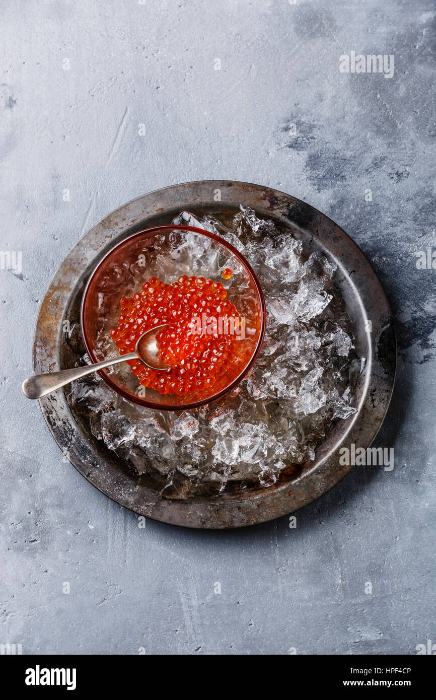 Red caviar in glass bowl on ice in metal plate on concrete background copy space Stock Photo