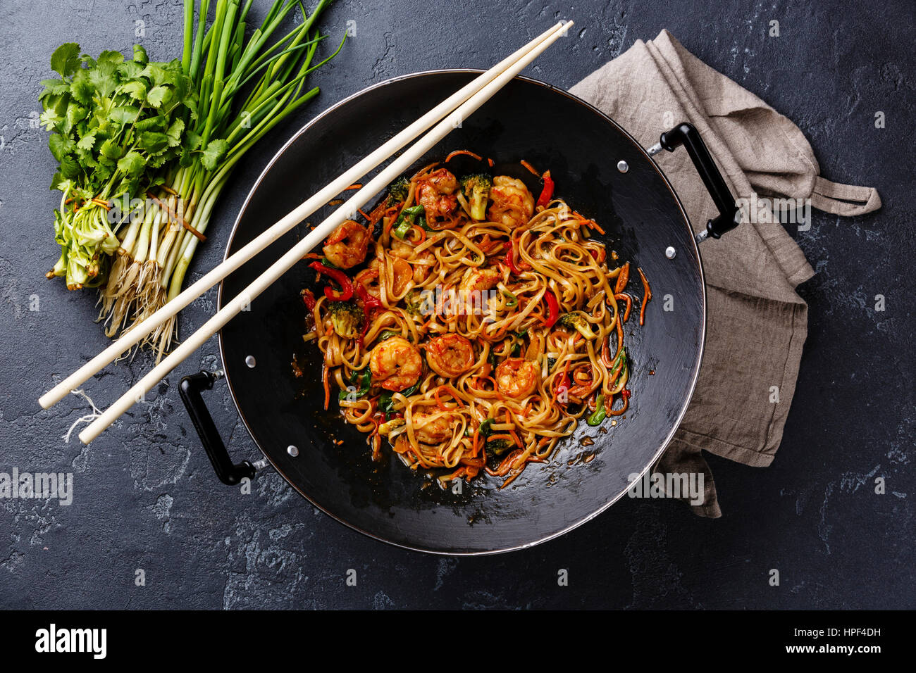 Udon stir-fry noodles with shrimp in wok pan on dark stone background Stock Photo