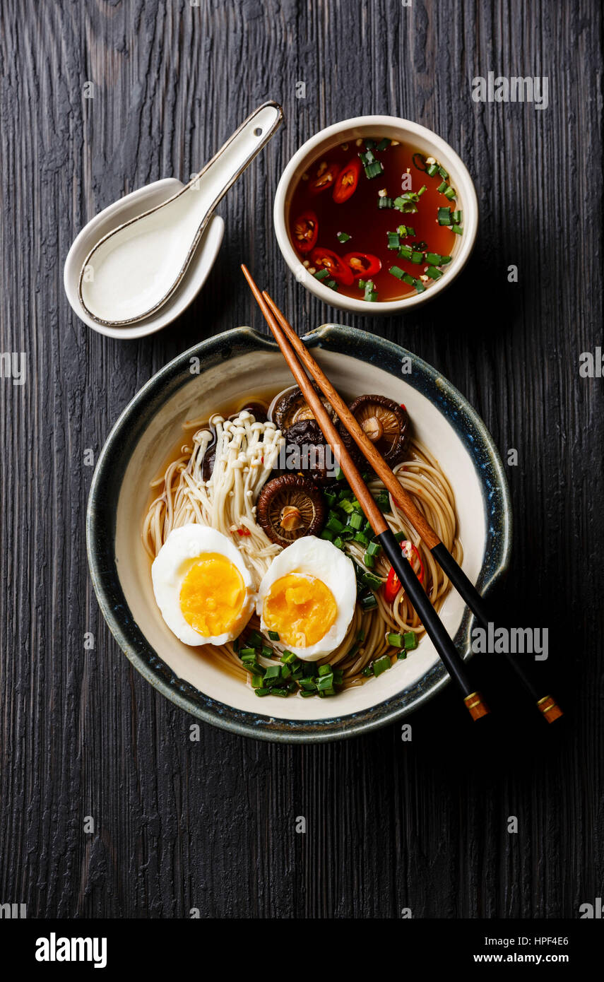 Ramen noodles with egg, enoki and shiitake mushrooms with broth on dark