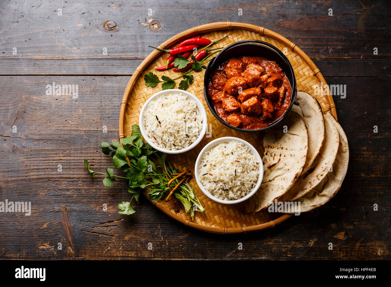 Chicken tikka masala spicy curry meat food in cast iron pot with rice and naan bread on wooden background Stock Photo