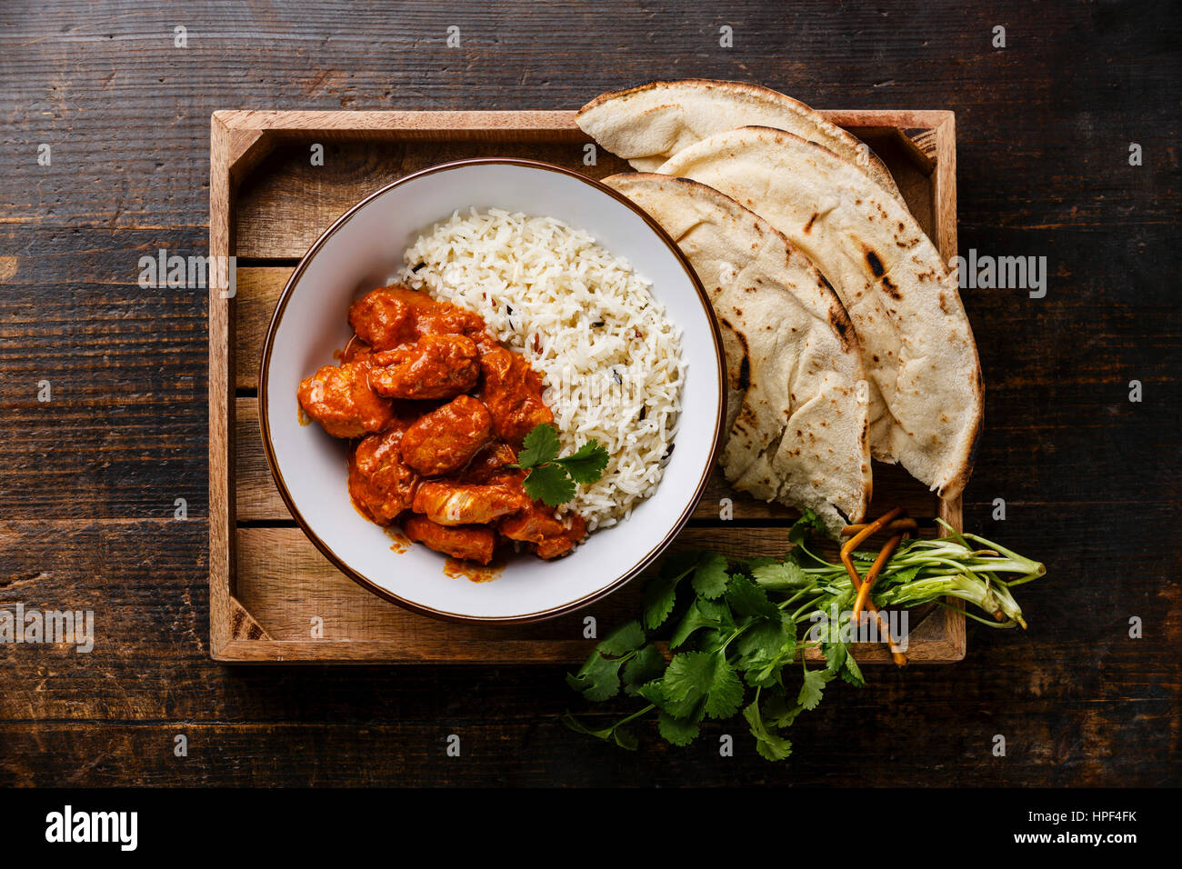 Chicken tikka masala spicy curry meat food with rice and naan bread in tray on wooden background Stock Photo
