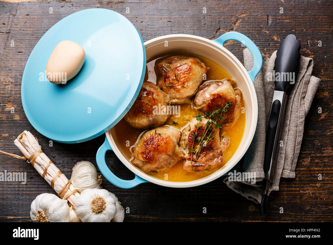 Roast chicken stew in cast iron pan on wooden background Stock Photo