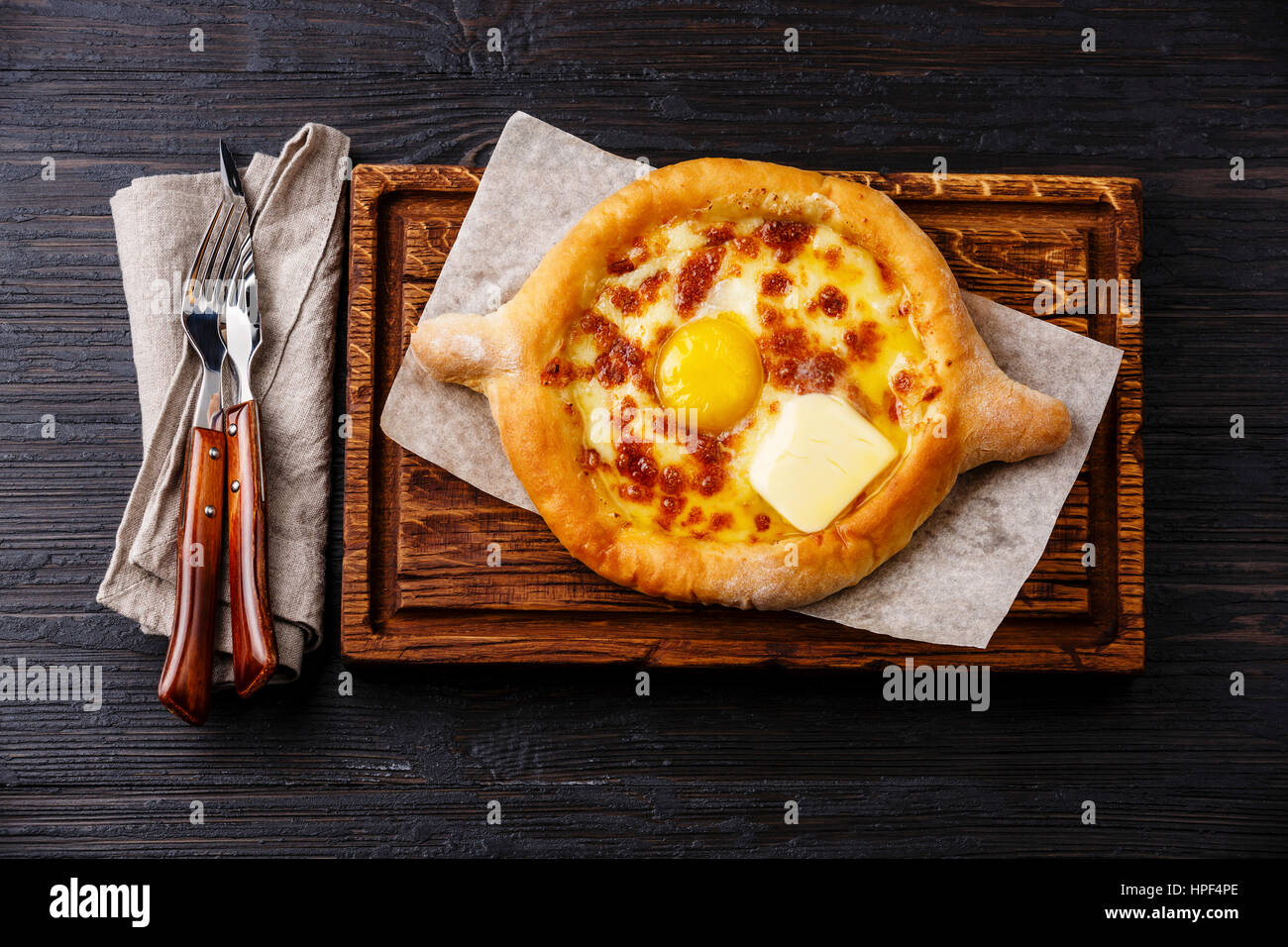 Ajarian Khachapuri traditional Georgian cheese pastry on burned black wooden background Stock Photo