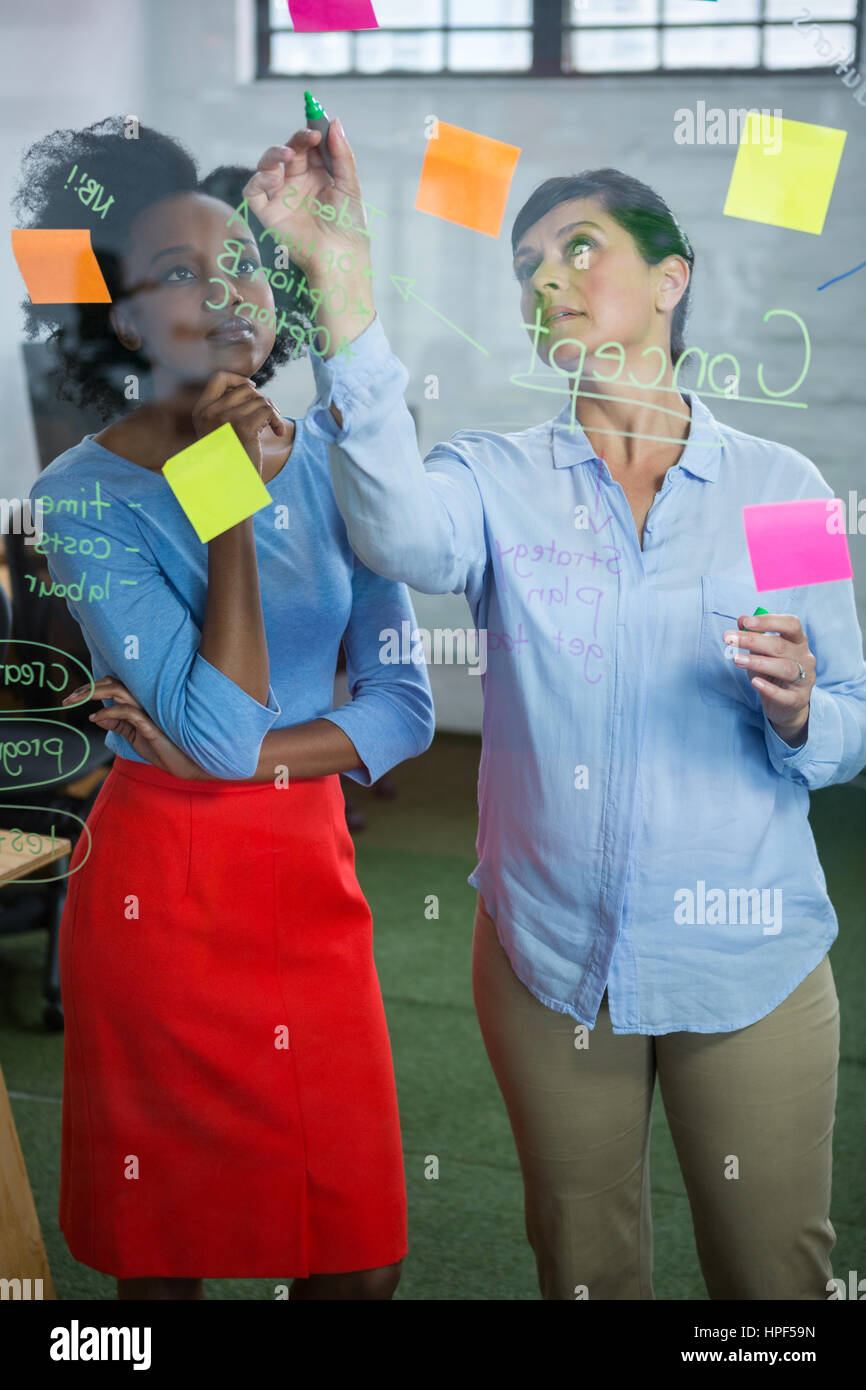 Female graphic designers writing on glass with marker Stock Photo - Alamy