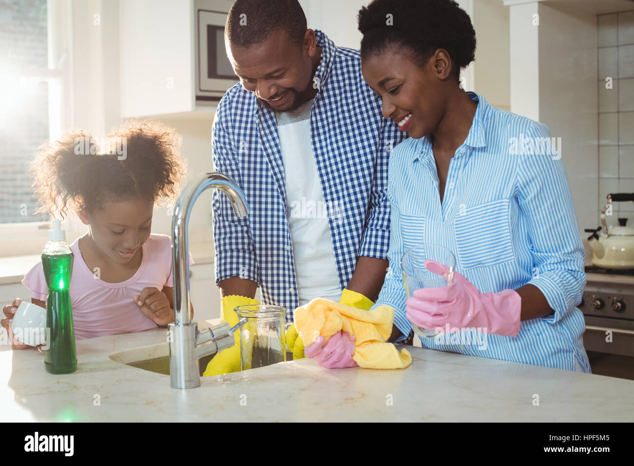 Family washing utensils in kitchen sink at home Stock Photo