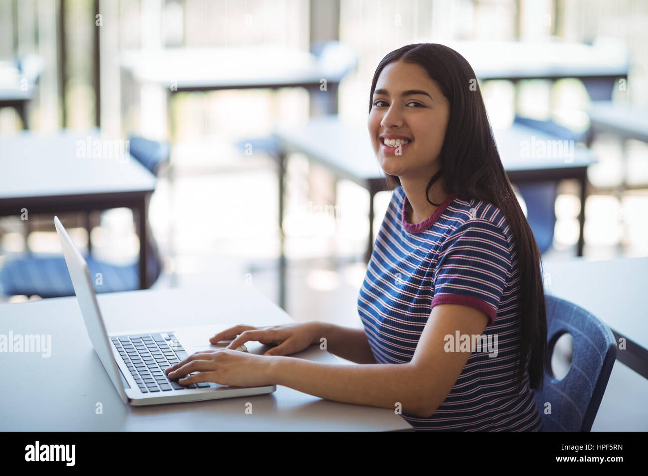 Portrait of schoolgirl using laptop in classroom at school Stock Photo ...