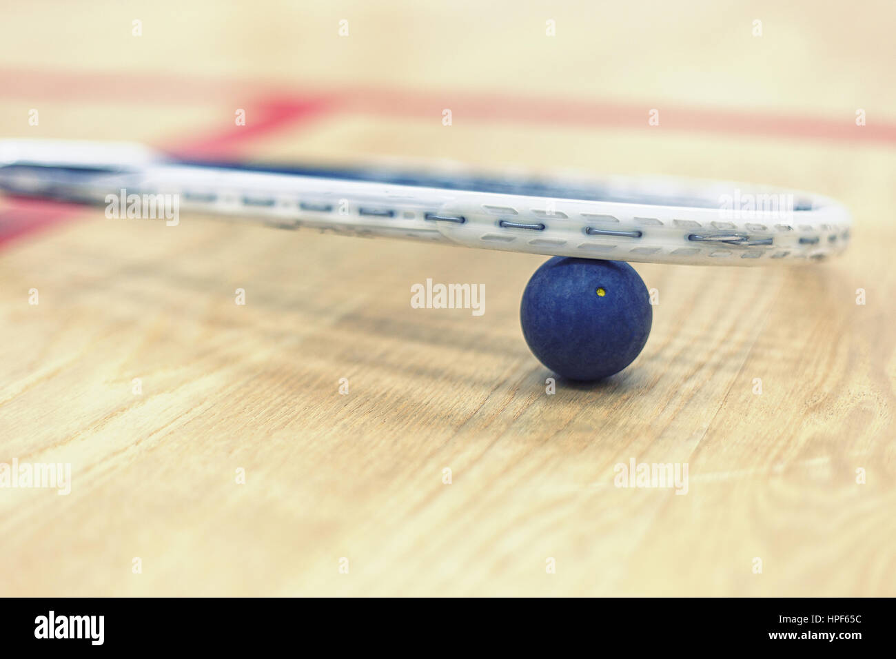 Close up of a squash racket and ball on the wooden background. Racquetball equipment. Squash ball between squash racket and floor on the court Stock Photo