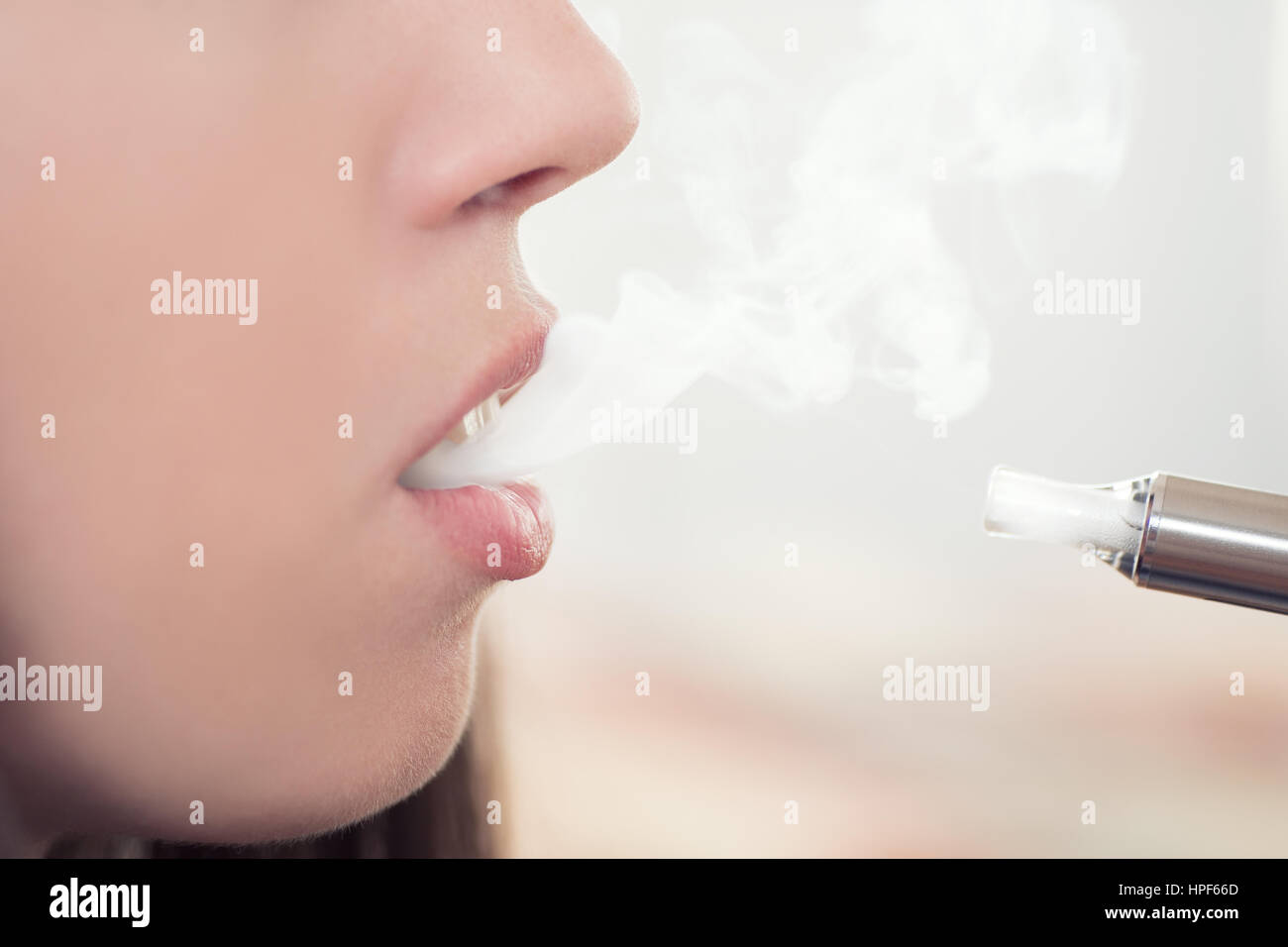 woman smoking electronic cigarette and enjoying smoke.Closeup detail of female with  electronic cigarette, horizontal shot. Girl smokes Stock Photo