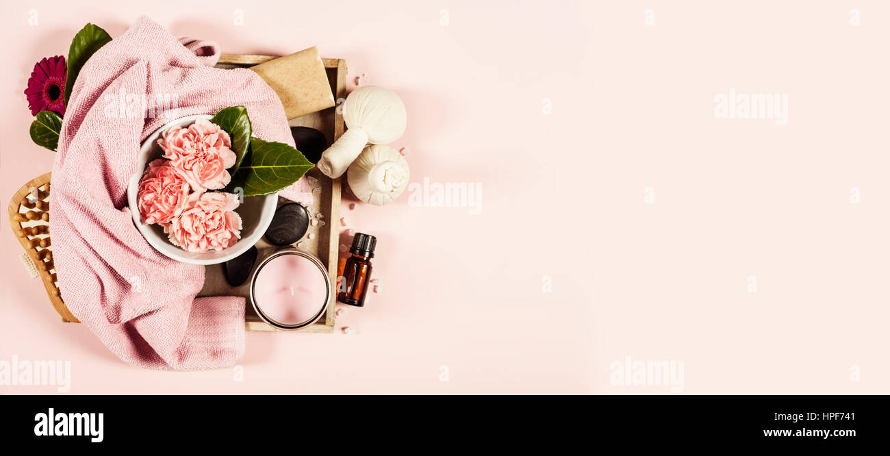 Spa background with sea salt, bowl ,flowers, water, soap bar, candles, essential oils, massage brush and flowers,top view. Flat lay. Pink background Stock Photo
