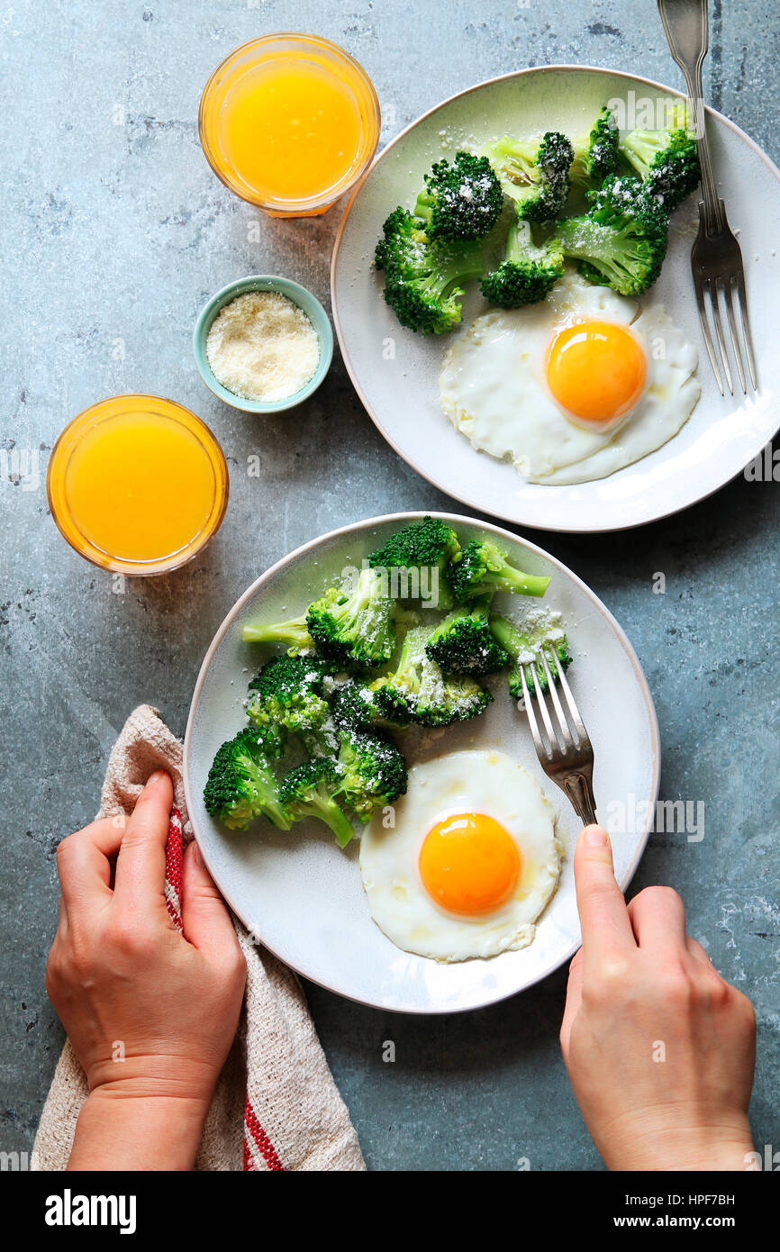 Steamed broccoli with parmesan cheese,fried eggs and a glass of orange juice for breakfast Stock Photo
