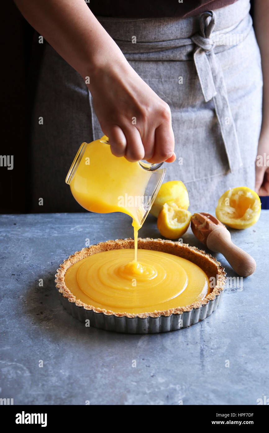 Female hand pouring lemon curd in a pastry shell. Stock Photo
