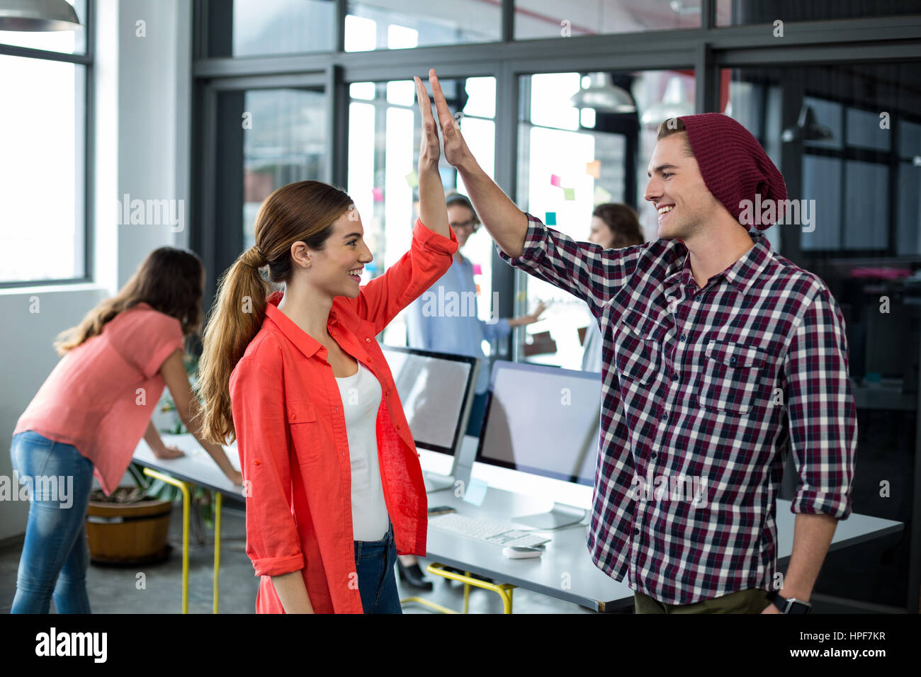 Happy business executives giving high five in office Stock Photo - Alamy