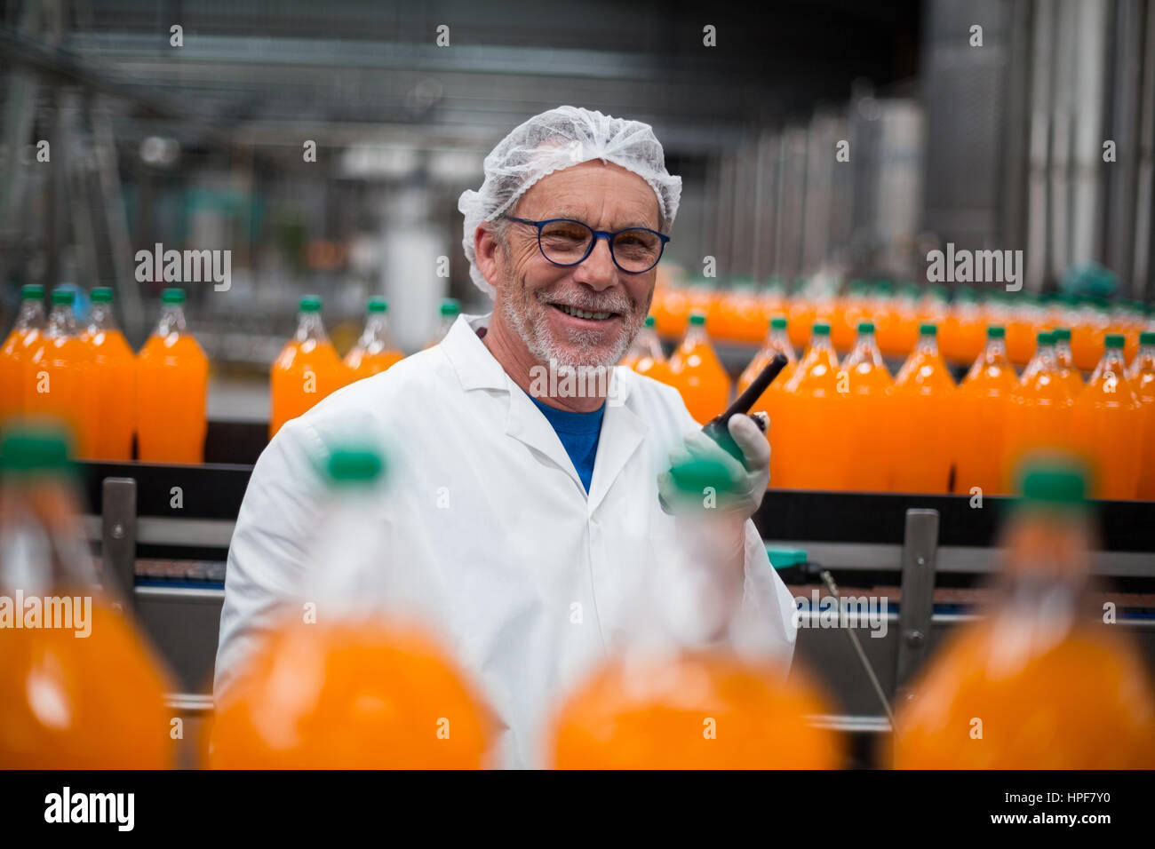 Portrait of smiling factory engineer standing near production line with