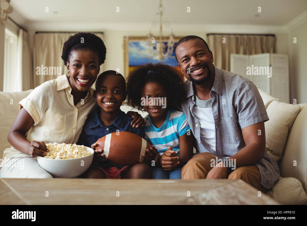 Portrait of parents and kids watching television in living room at home Stock Photo