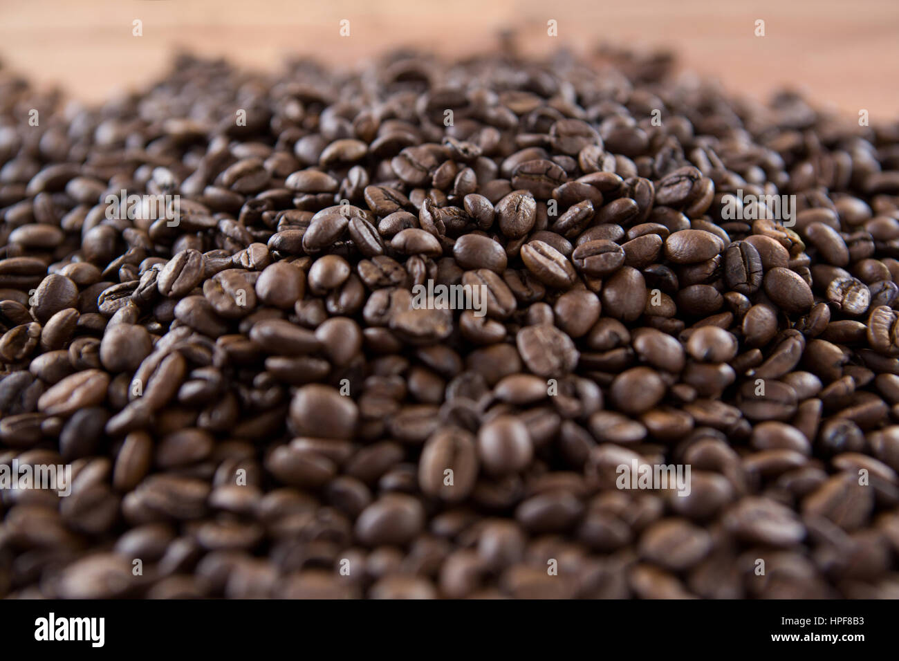 Pile of roasted coffee beans on wooden table Stock Photo - Alamy