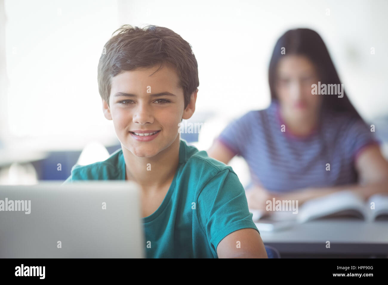 Portrait of happy schoolboy using laptop in classroom at school Stock ...