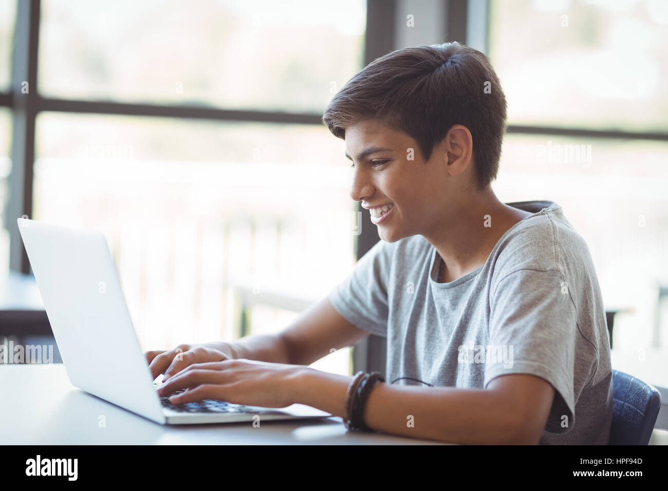 Happy schoolboy using laptop in classroom at school Stock Photo - Alamy