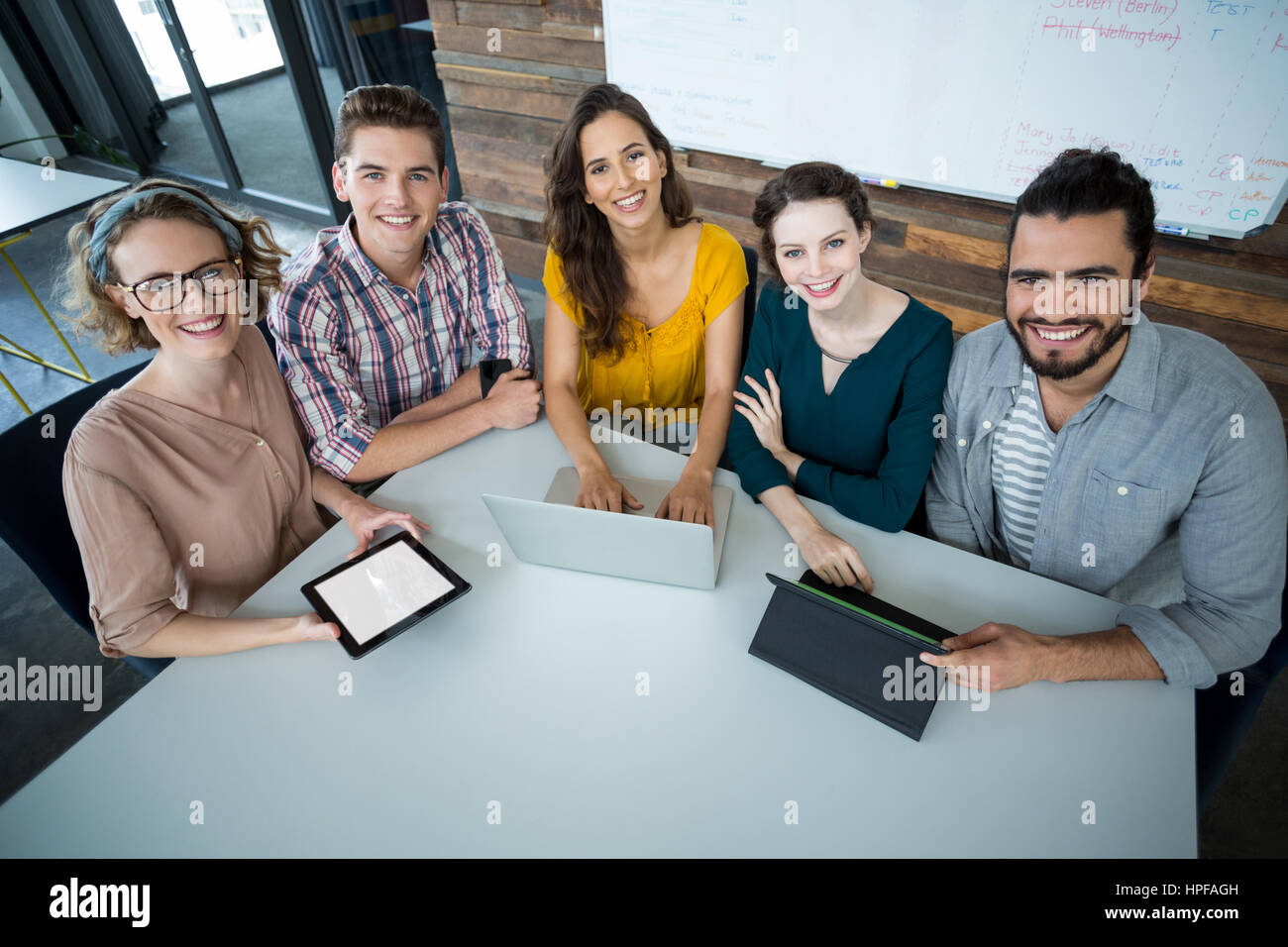 Portrait of smiling business executives sitting in office with digital ...