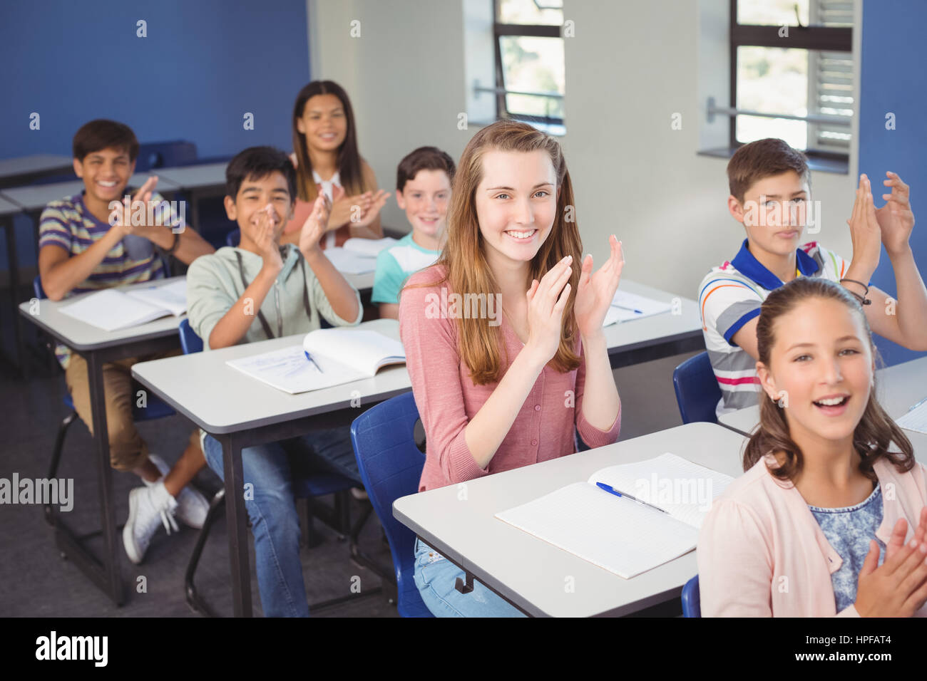 Portrait of schoolgirl clapping hands in classroom at school Stock