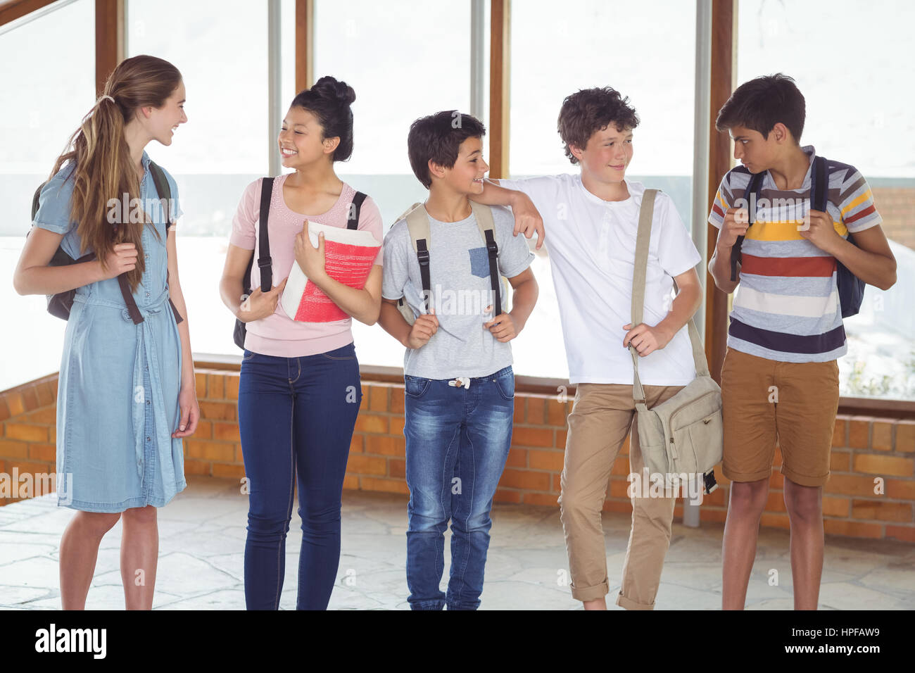 Happy students interacting with each other in corridor at school Stock Photo