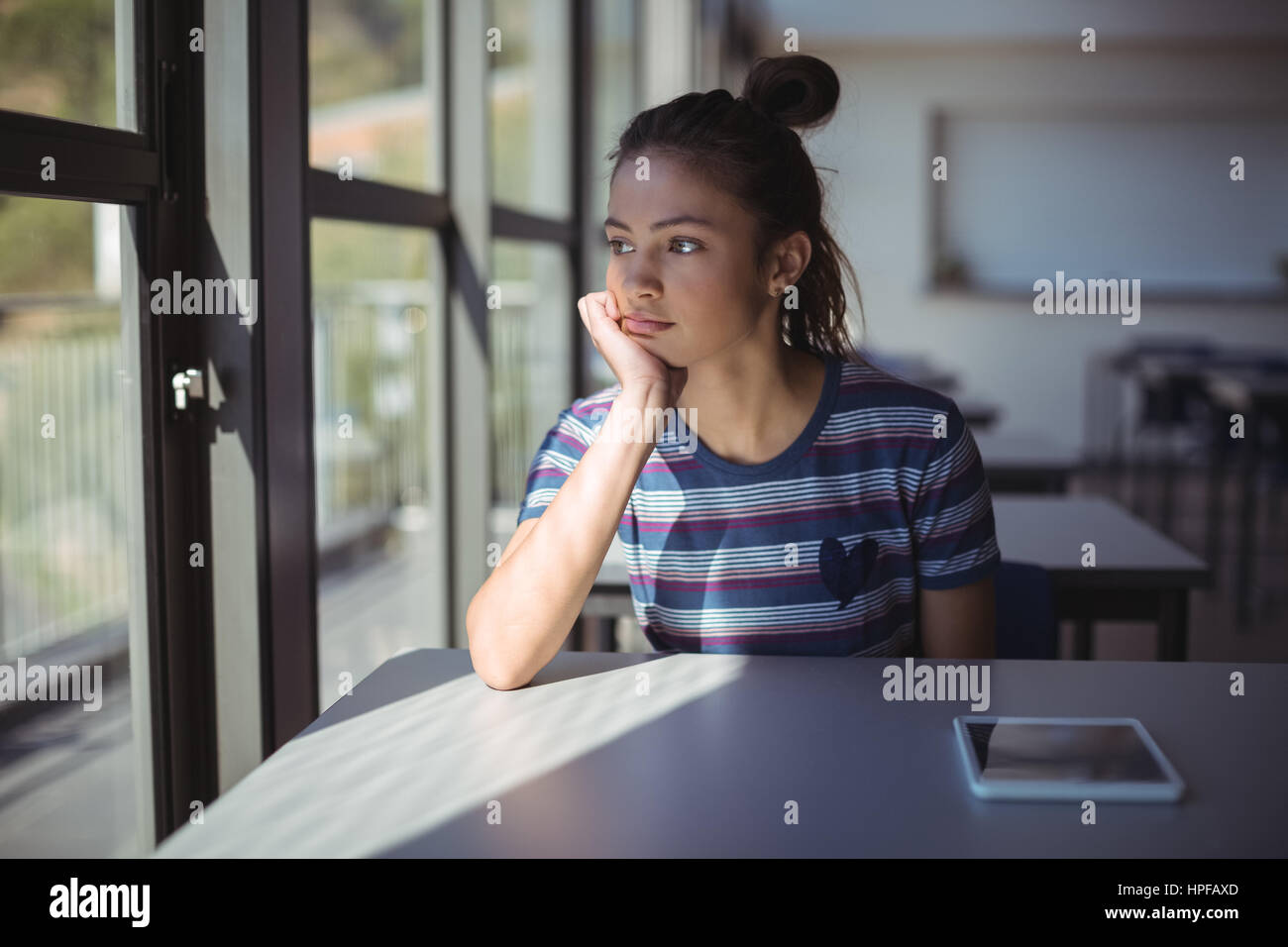 Thoughtful schoolgirl sitting in classroom at school Stock Photo - Alamy