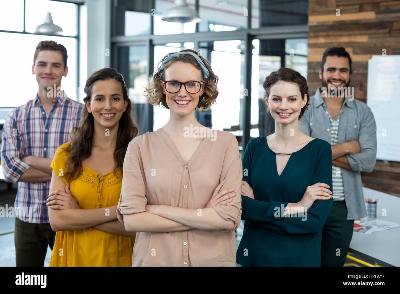 Portrait of smiling business executives standing with arms crossed in ...