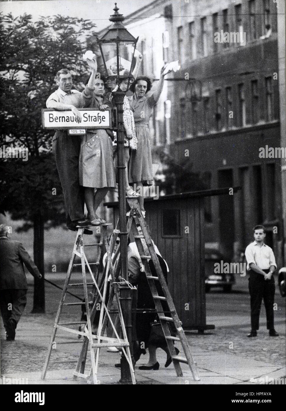 West Berliners stand on ladders to greet friends and loved ones on the eastern side of the Berlin Wall, West Berlin, Germany, 01/01/1961. Stock Photo