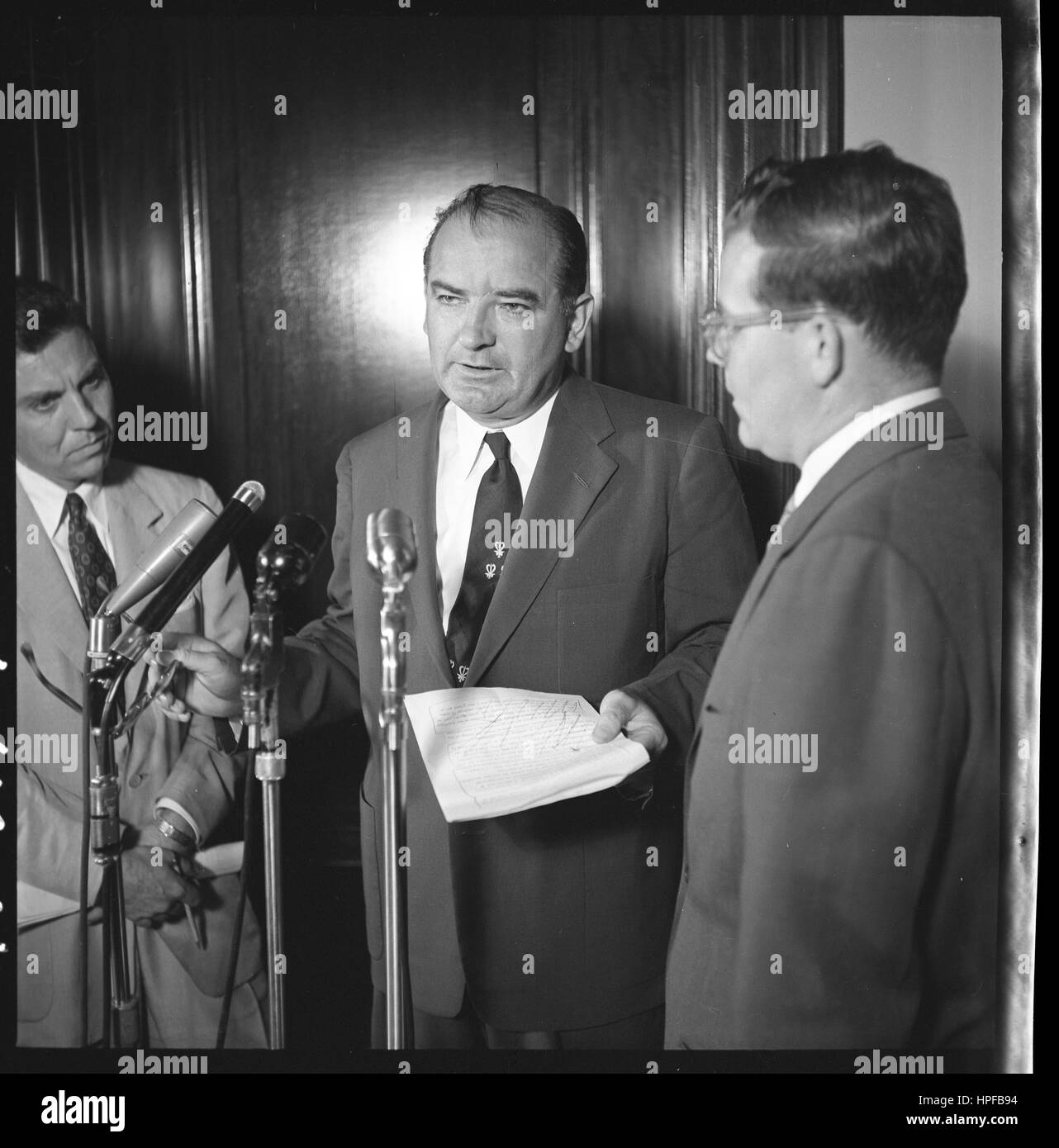 Senator Joseph McCarthy standing at microphone with two other men at the U S Capitol, Washington, DC, 06/01/1954. Photo by Thomas O'Halloran Stock Photo