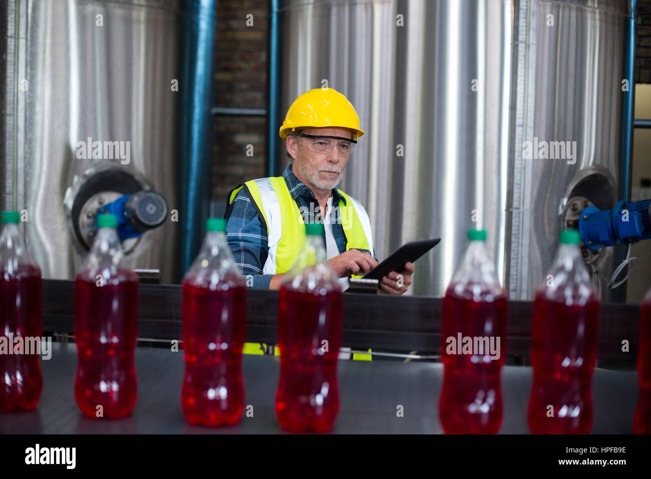 Male factory worker monitoring cold drink bottles at drinks production