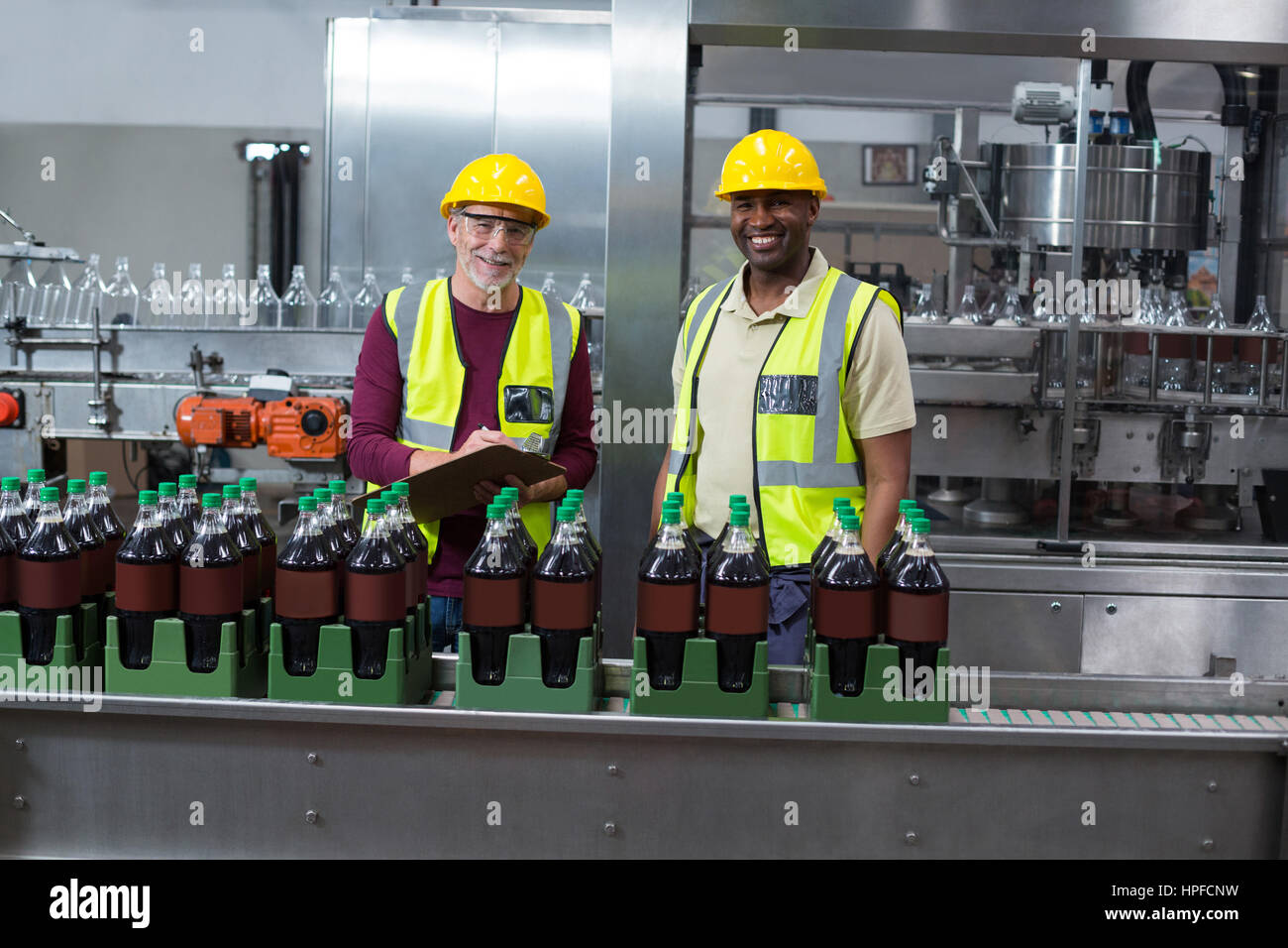 Portrait of two factory workers monitoring cold drink bottles at drinks