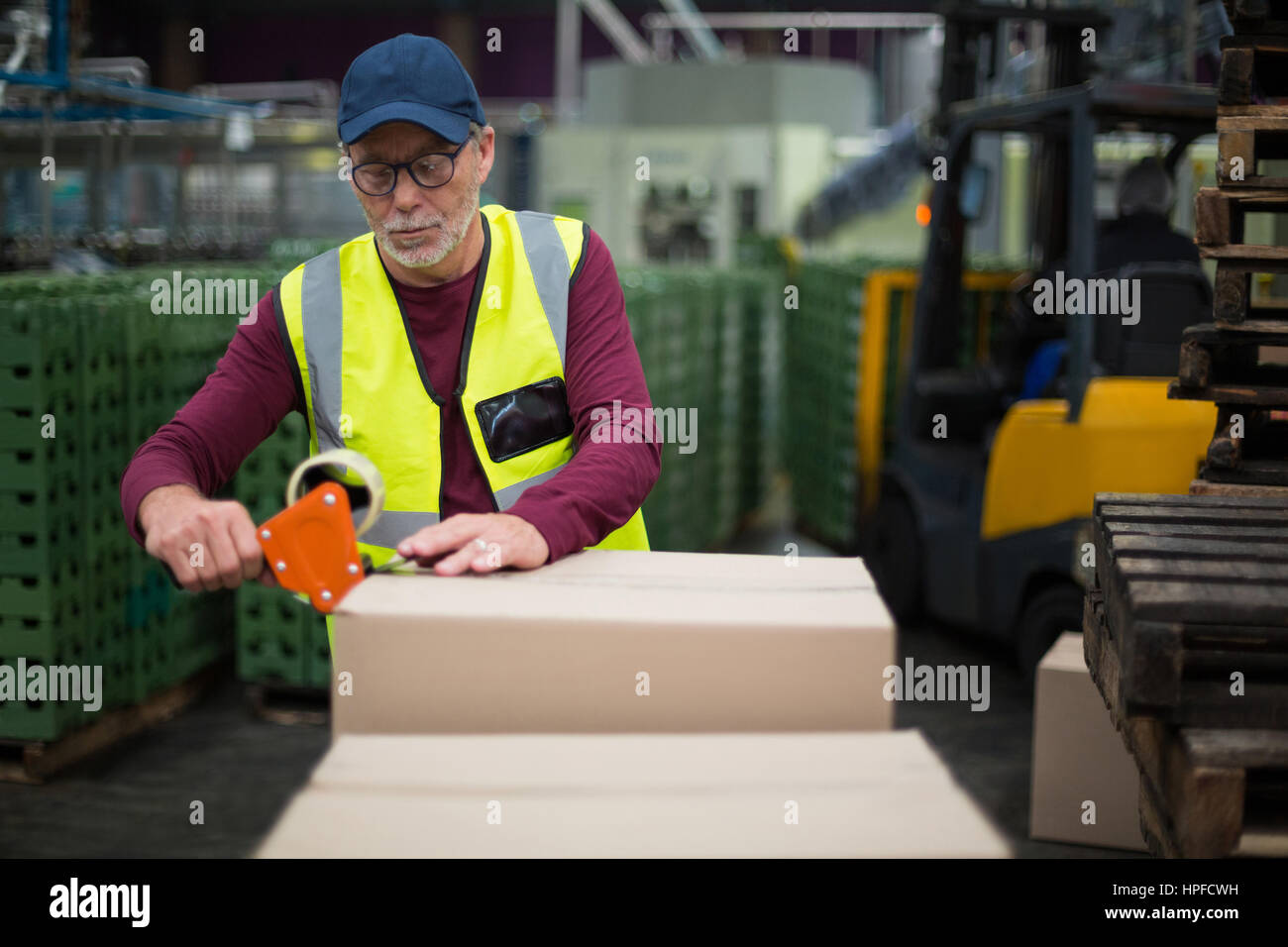 Factory worker sealing cardboard boxes in drinks production factory