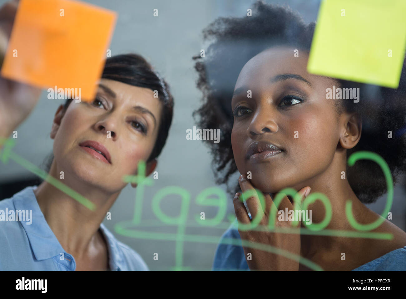 Female graphic designers writing on glass with marker Stock Photo - Alamy