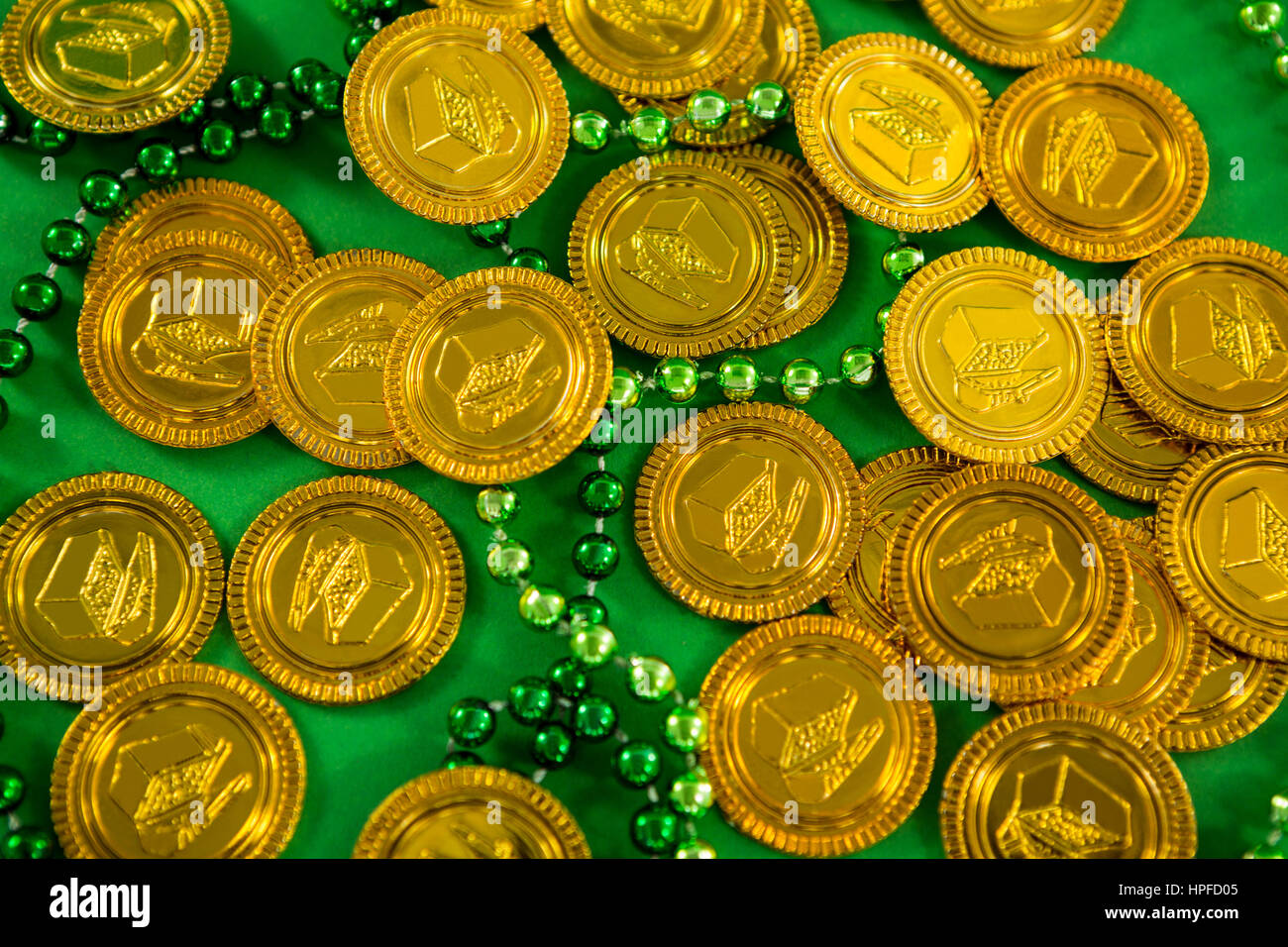 St Patricks Day gold chocolate coins and beads on green background ...