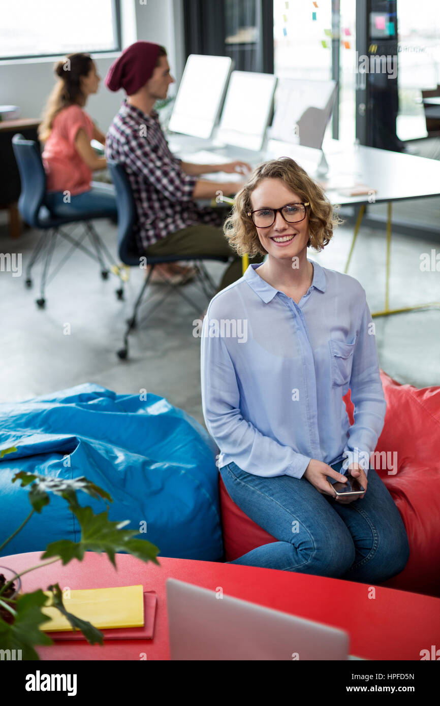 Portrait of smiling female business executive sitting in office while ...