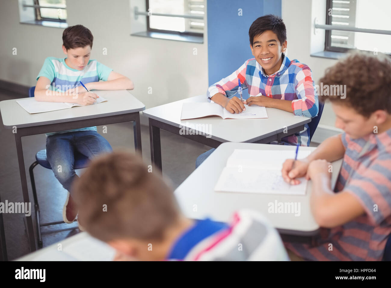 Portrait of schoolboy sitting at desk in classroom Stock Photo - Alamy