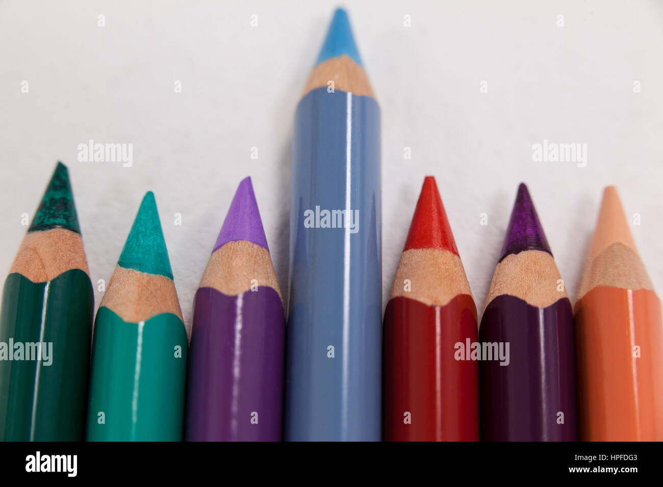 Blue pencil standing out from a row of colored pencils on white