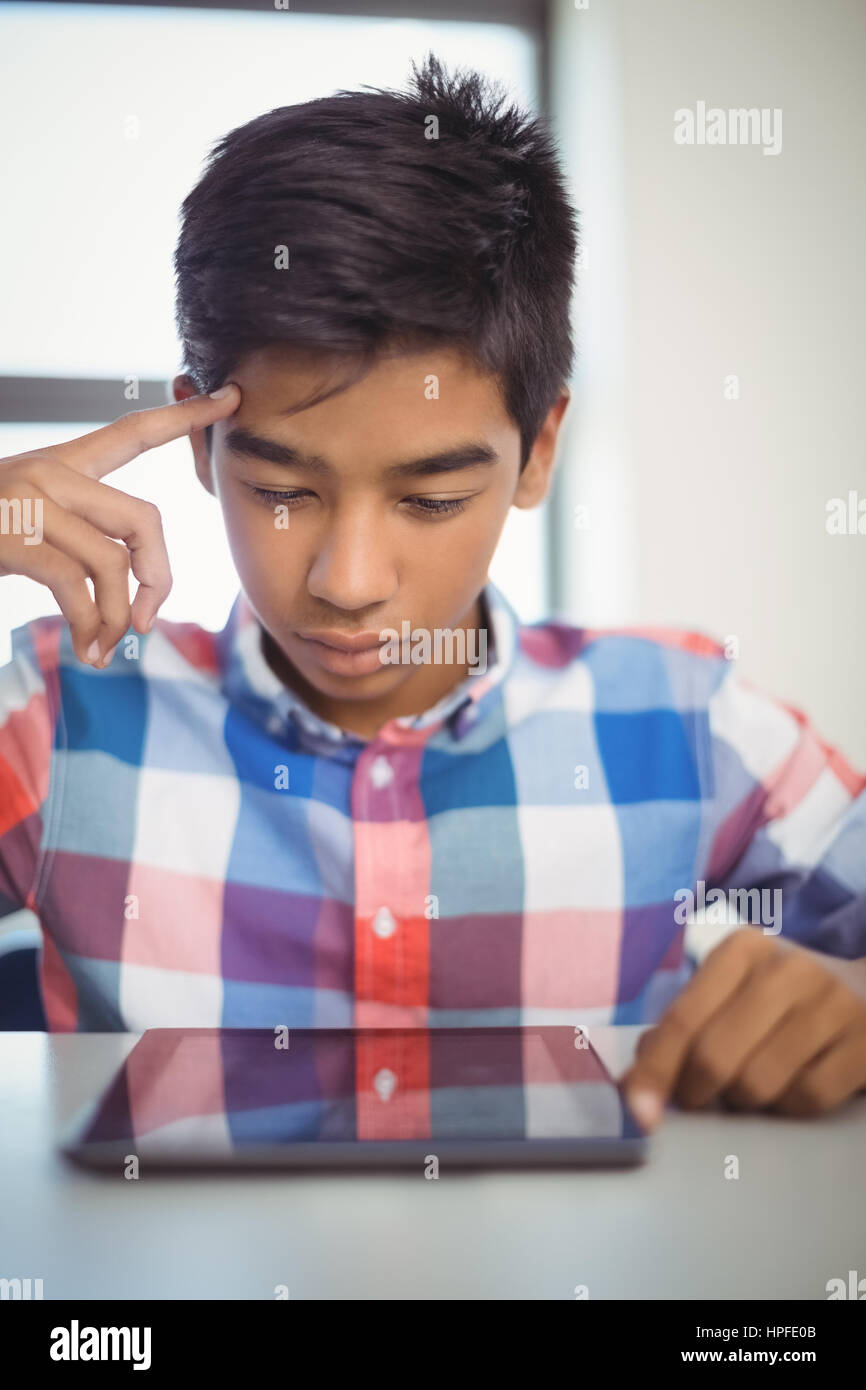Schoolboy using digital tablet at desk in classroom Stock Photo - Alamy