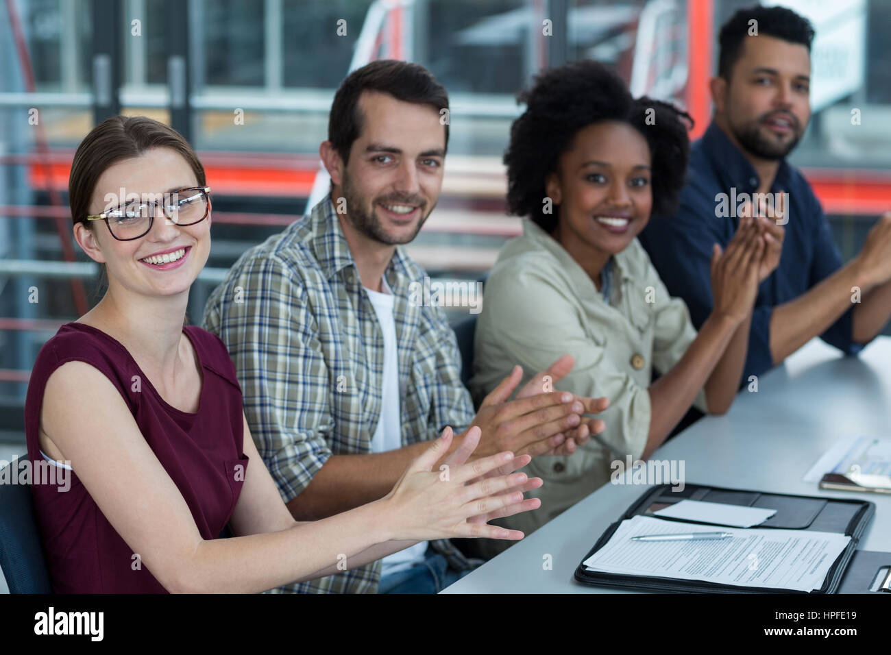 Portrait of smiling business executives clapping in meeting at office ...