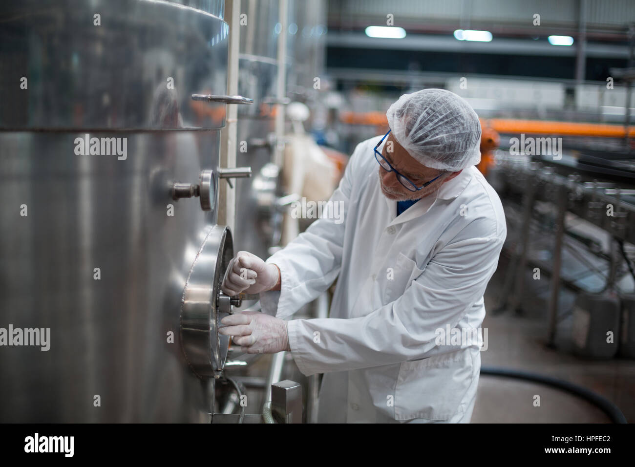 Factory engineer turning control wheel of storage tank in bottle