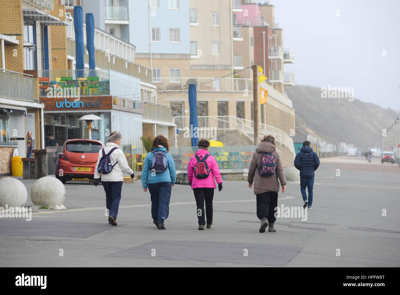 Group of women with rucksacks walking along the promenade in strong winds during Storm Doris, February 2017, Boscombe, Dorset Stock Photo