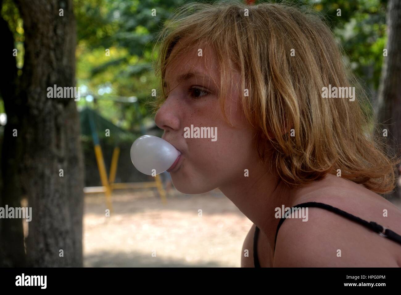 Girl of the side makes a small bubble with chewing gum Stock Photo